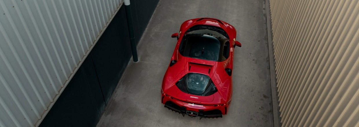 Red Ferrari SF90 Stradale seen from above and behind, parked in a concrete laneway